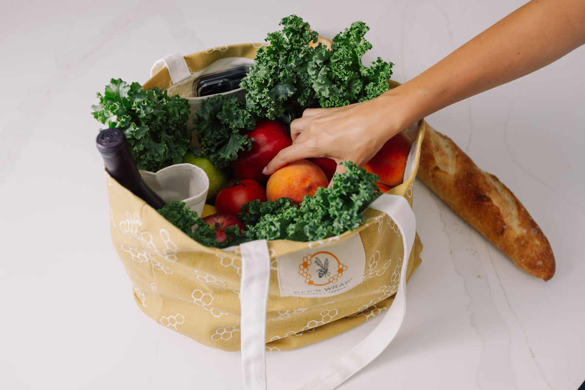 Reusable grocery bag filled with fresh produce on a white background