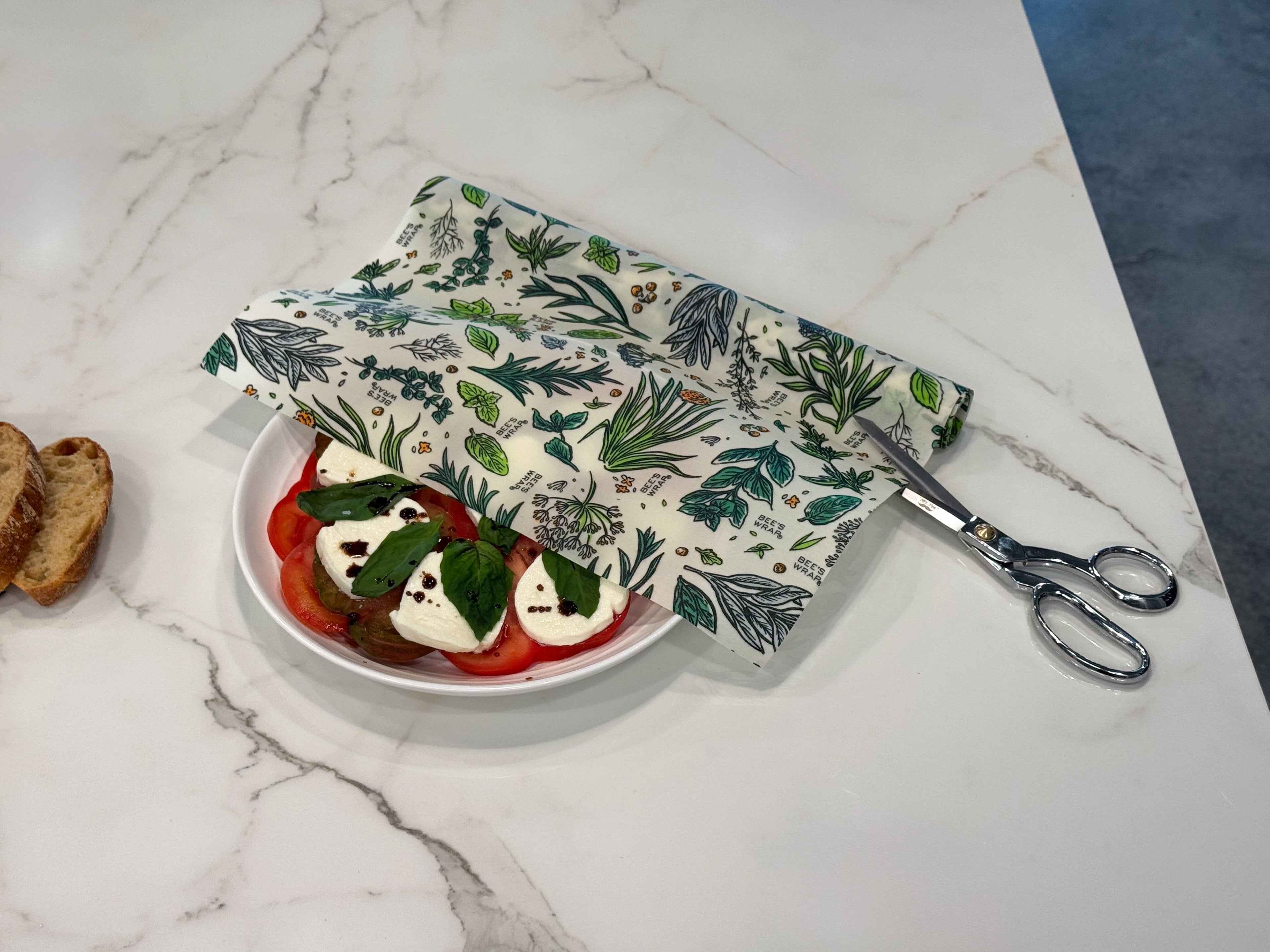 Roll XXL Roll Bee's Wrap with scissors over a caprese salad